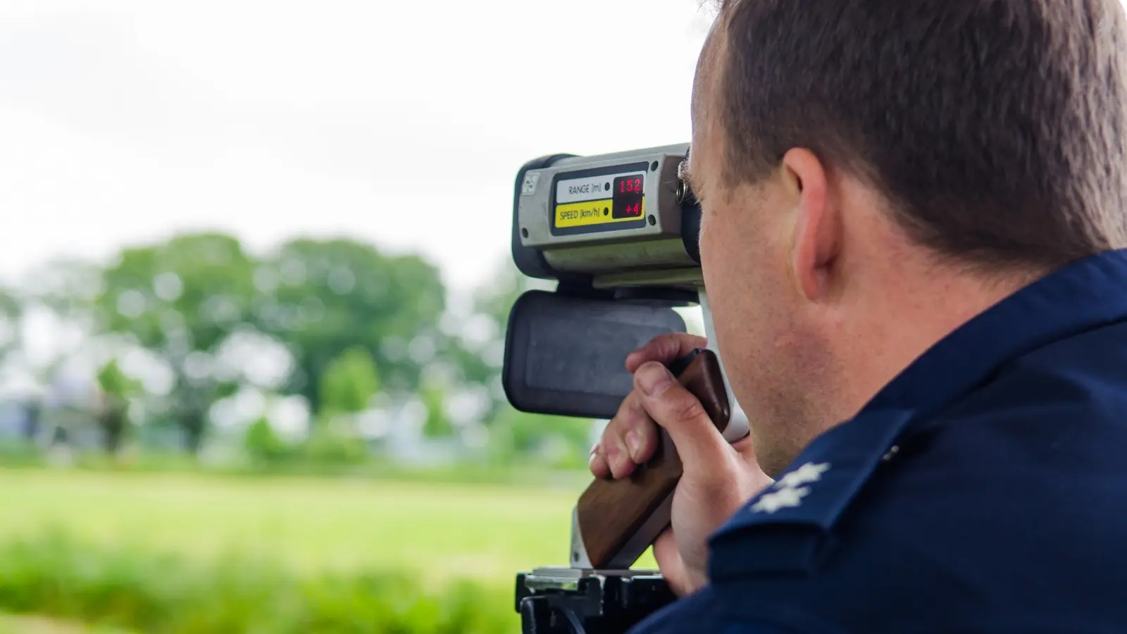 Symbolbild: Ein Polizeibeamter nutzt die Laserpistole TraffiPatrol XR zur Geschwindigkeitsmessung am Straßenrand.